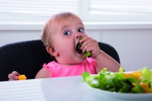 Litet barn äter råa grönsaker
