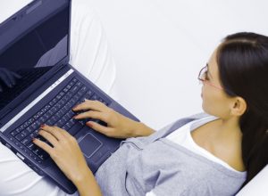 Ung kvinna med laptop i knät