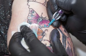 Tatuerare gör en färggrann tauering på en arm