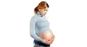 Gravid kvinna håller o och tittar ned på sin mage