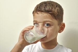 Pojke dricker ur ett glas mjölk