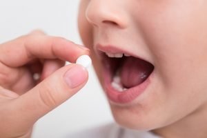 Barn gapar för att svälja vit tablett