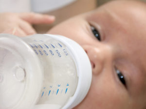 Baby dricker mjölk från nappflaska