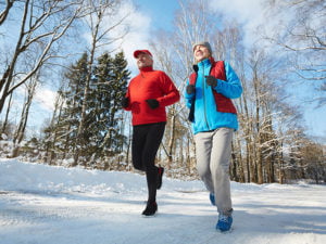 Äldre par joggar på snöig väg