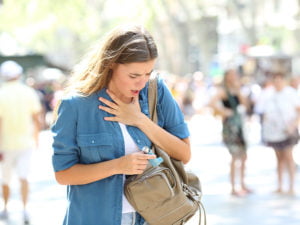 Ung kvinna tar upp astmainhalator ur sin väska