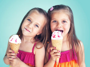 Två flickor äter varsin glasstrut