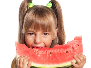 Flicka äter på en stor skiva vattenmelon
