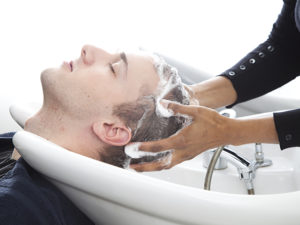 Frisörhänder tvättar håret på man