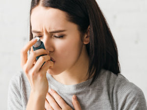 Kvinna inhalerar astmamedicin