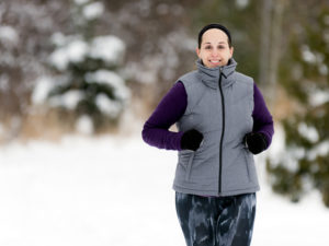 Kvinna joggar mot kameran i snöigt landskap