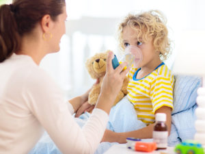 Mamma hjälper liten son att andas in astmamedicin