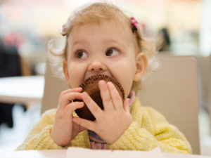 Liten flicka äter chokladmuffins