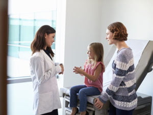 Kvinnlig läkare med mamma och dotter i undersökningsrum